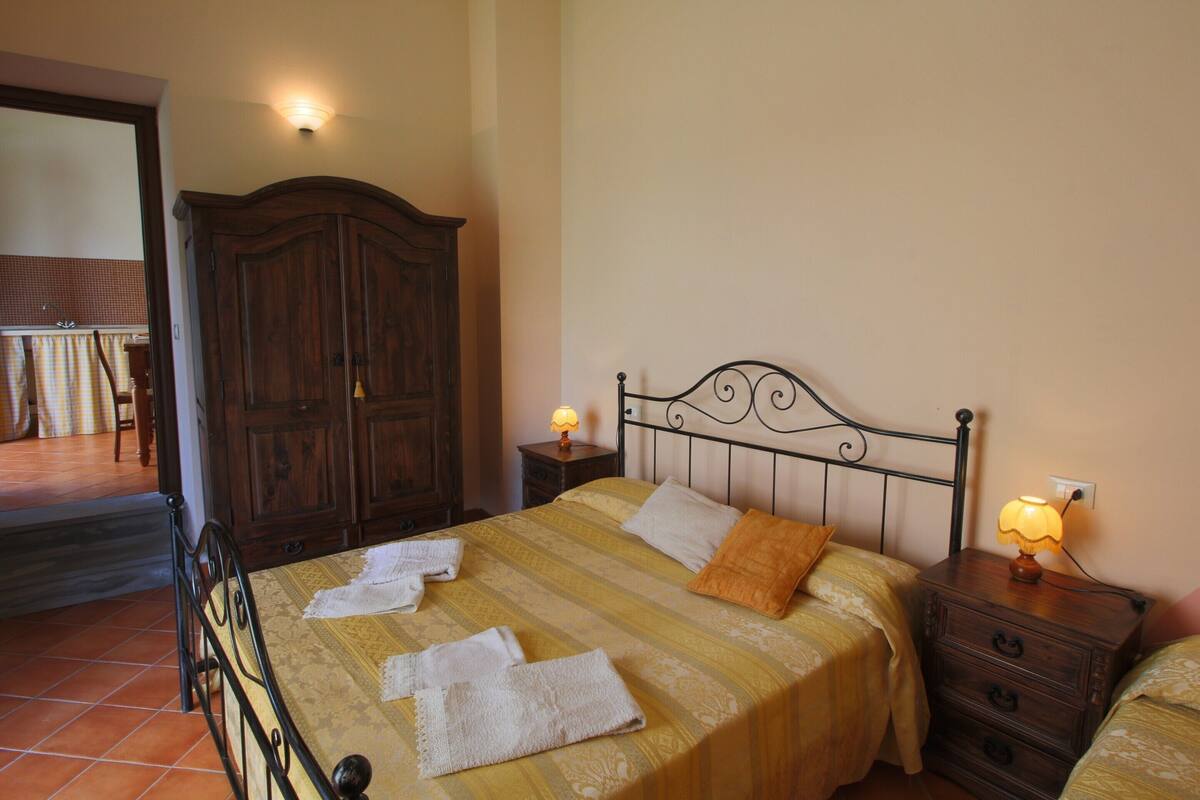 A bedroom with a bed, a nightstand, a wardrobe, and a lamp.