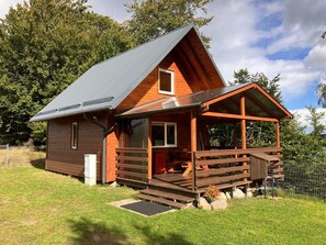 A wooden cabin with a sloped roof, a porch, and a small window. - Cottage in a Quiet Location by the Lake Mausz, Parchowo in Kashubia (Parchowo)