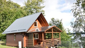 Une cabane en bois avec un toit en pente, une véranda et une vue sur un lac.