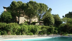 A swimming pool with a stone building in the background, surrounded by trees and greenery. - Cosy Apartment in Mantignana With Private Terrace (Corciano)