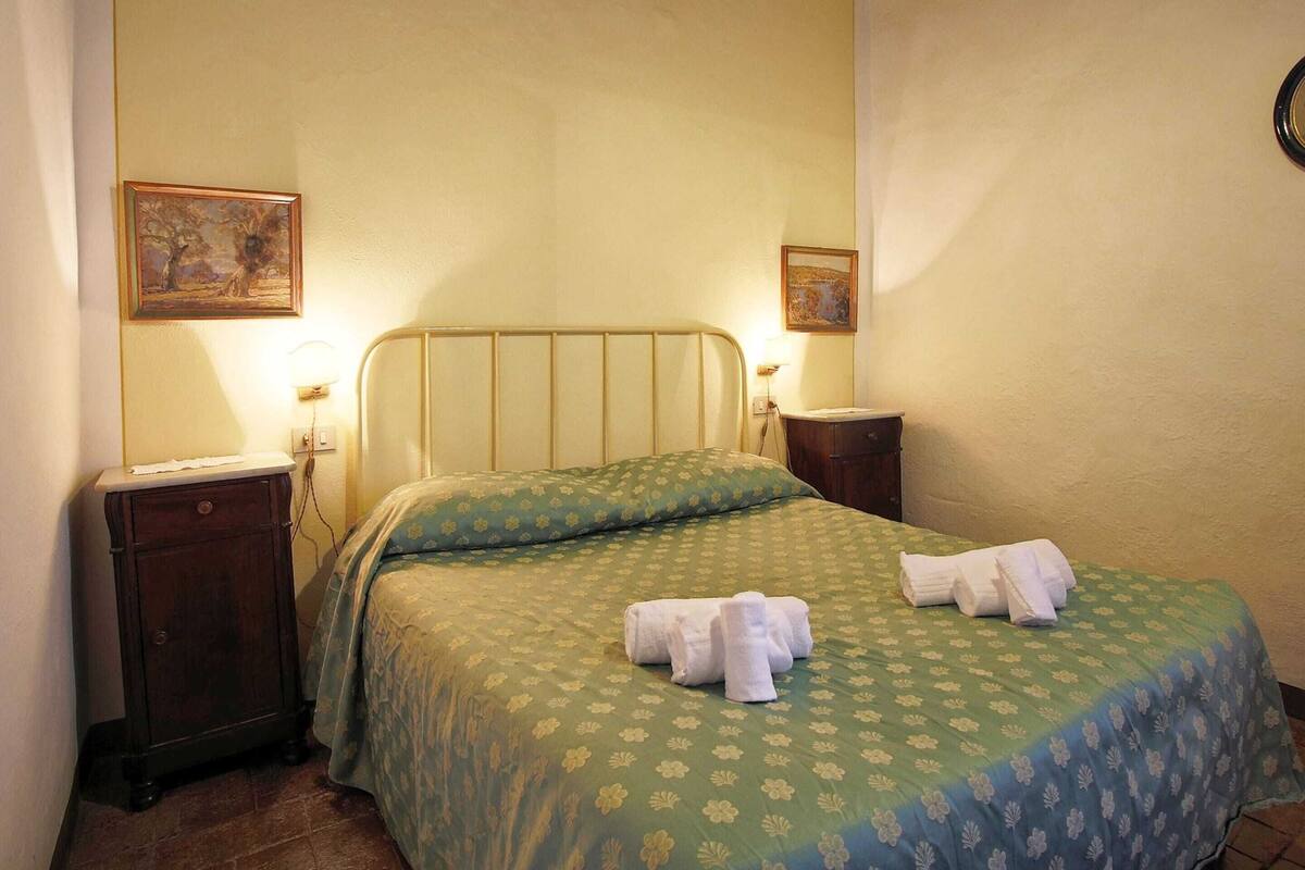 Une chambre à coucher comprenant un lit, deux tables de chevet et deux lampes fixées au mur.