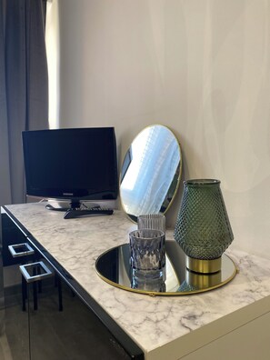 Enjoy a minimalist retreat with a flat-screen TV, stylish lamp, and elegant mirror.