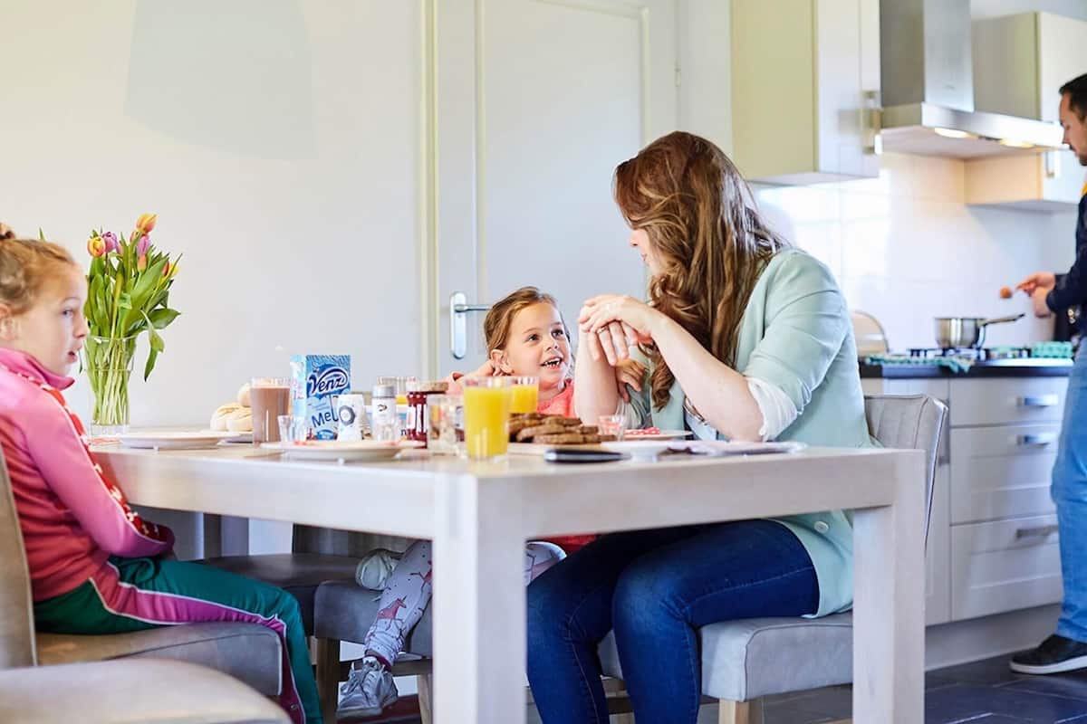 A family dining in a modern kitchen with a dining table, chairs, and a kitchen counter.
