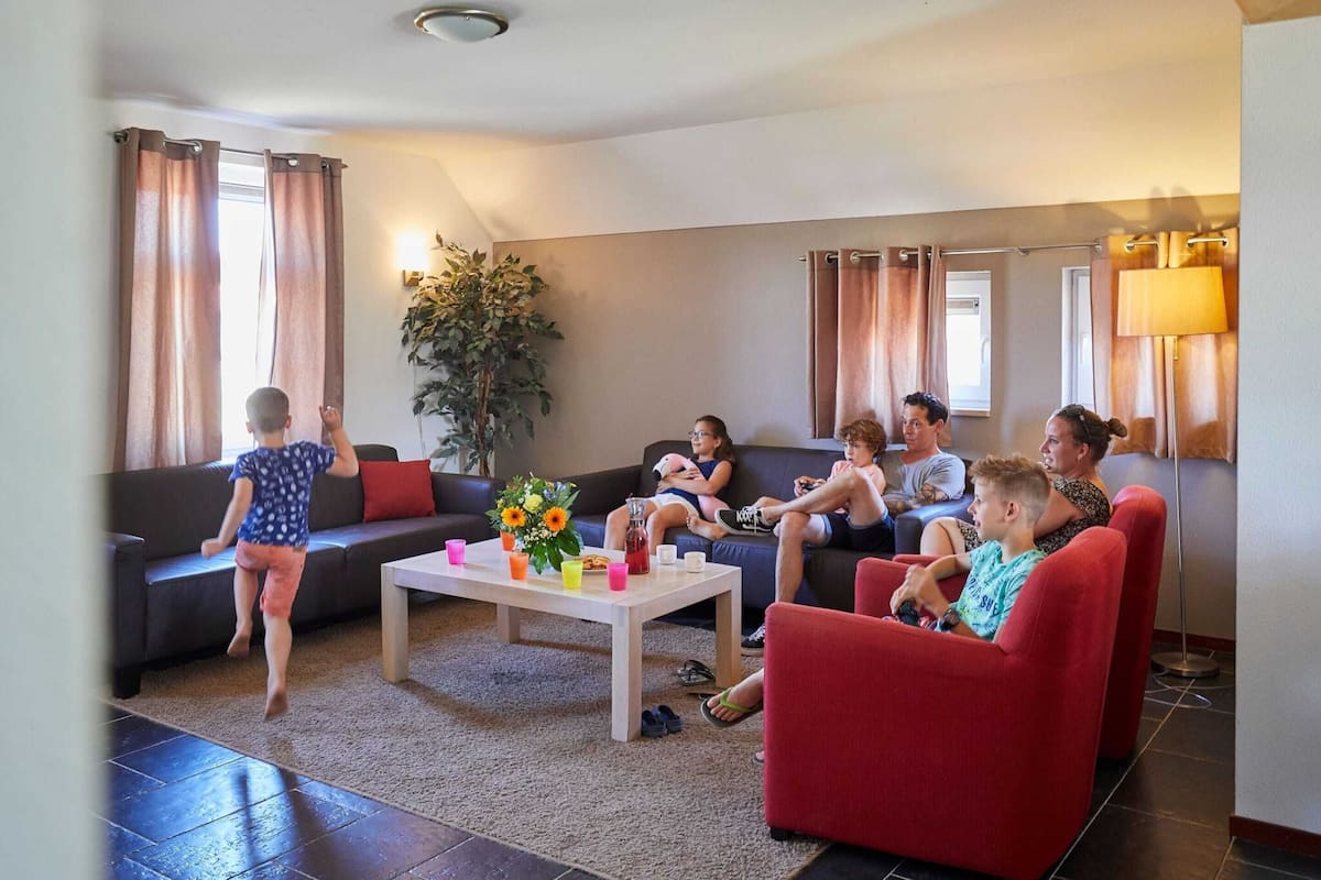 A living room with a sofa, a coffee table with drinks, and a plant.