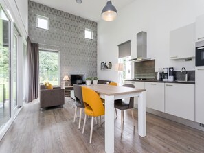 A modern kitchen with a dining area, large windows, and a view of greenery. - Nice Villa With Sauna, Whirlpool & Steam Shower (Roggel)