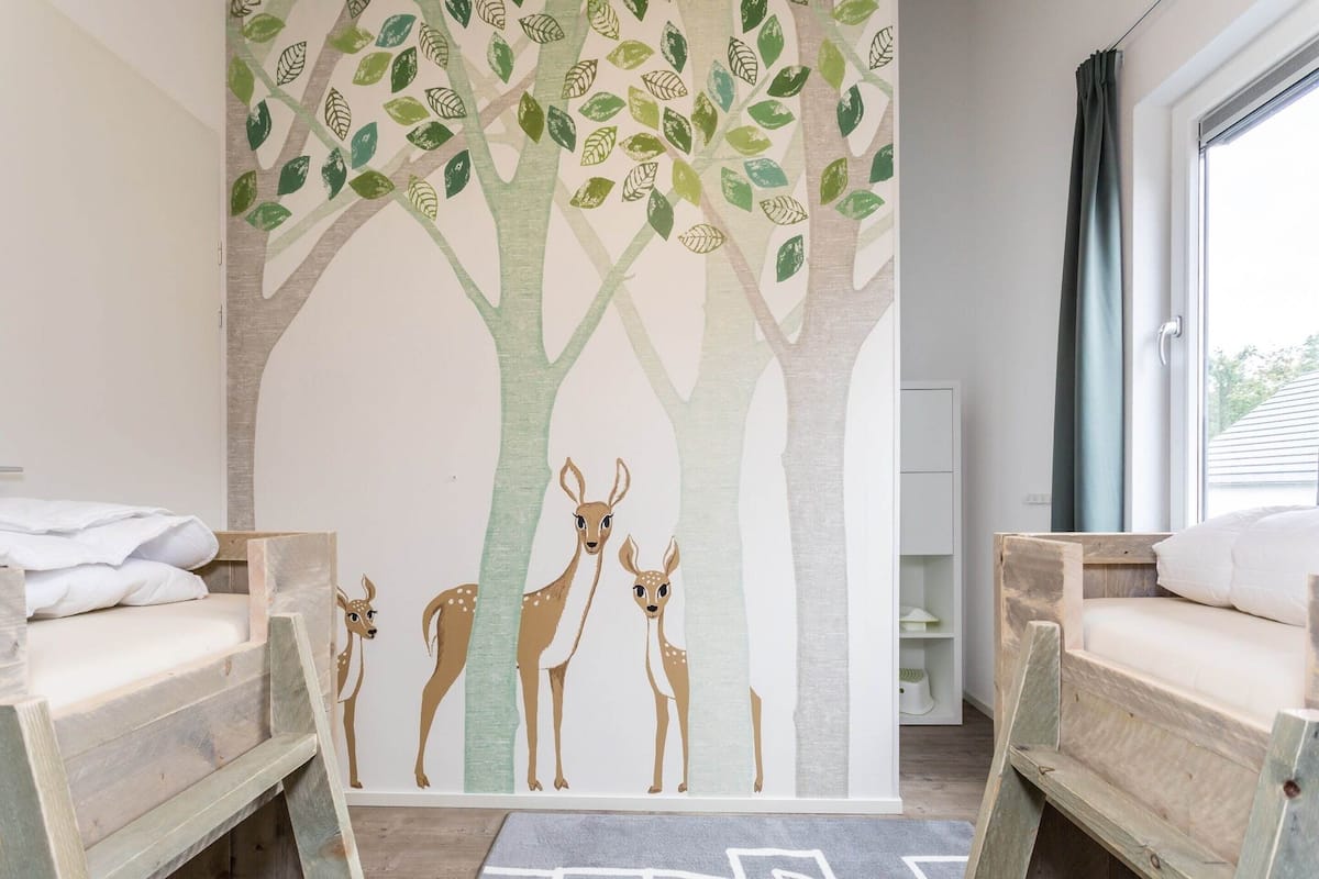 A children's room with a mural of deer on a tree, two bunk beds, and a hopscotch game on the floor.