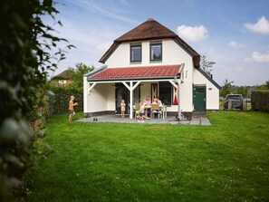 A two-story house with a red-tiled roof, a covered porch, and a green lawn. - Nice Villa With Sauna, Whirlpool & Steam Shower (Roggel)