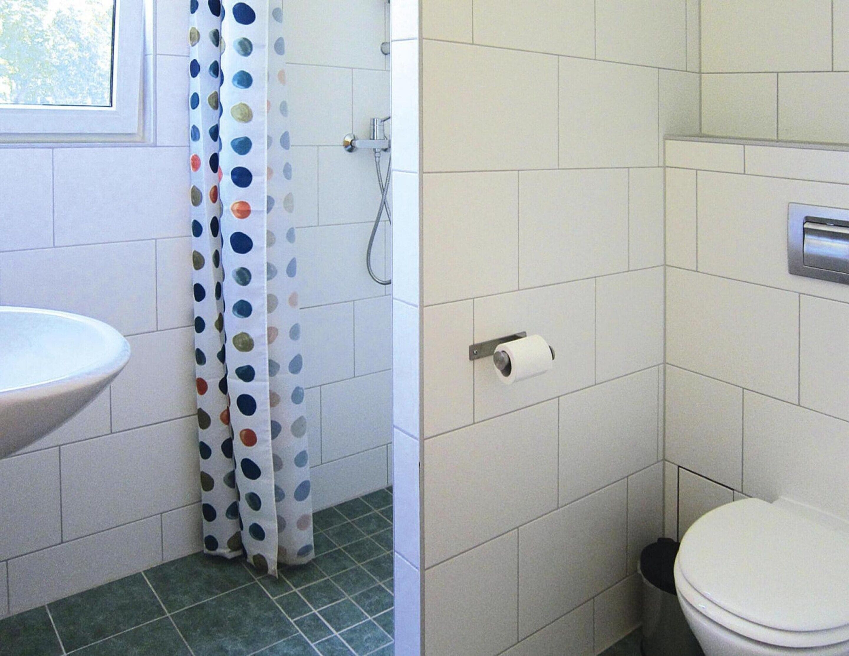 Een badkamer met een wit wastafelmeubel, toilet en douchegedeelte.
