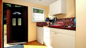 Una cocina compacta con lavavajillas, cafetera y un escurreplatos rojo.