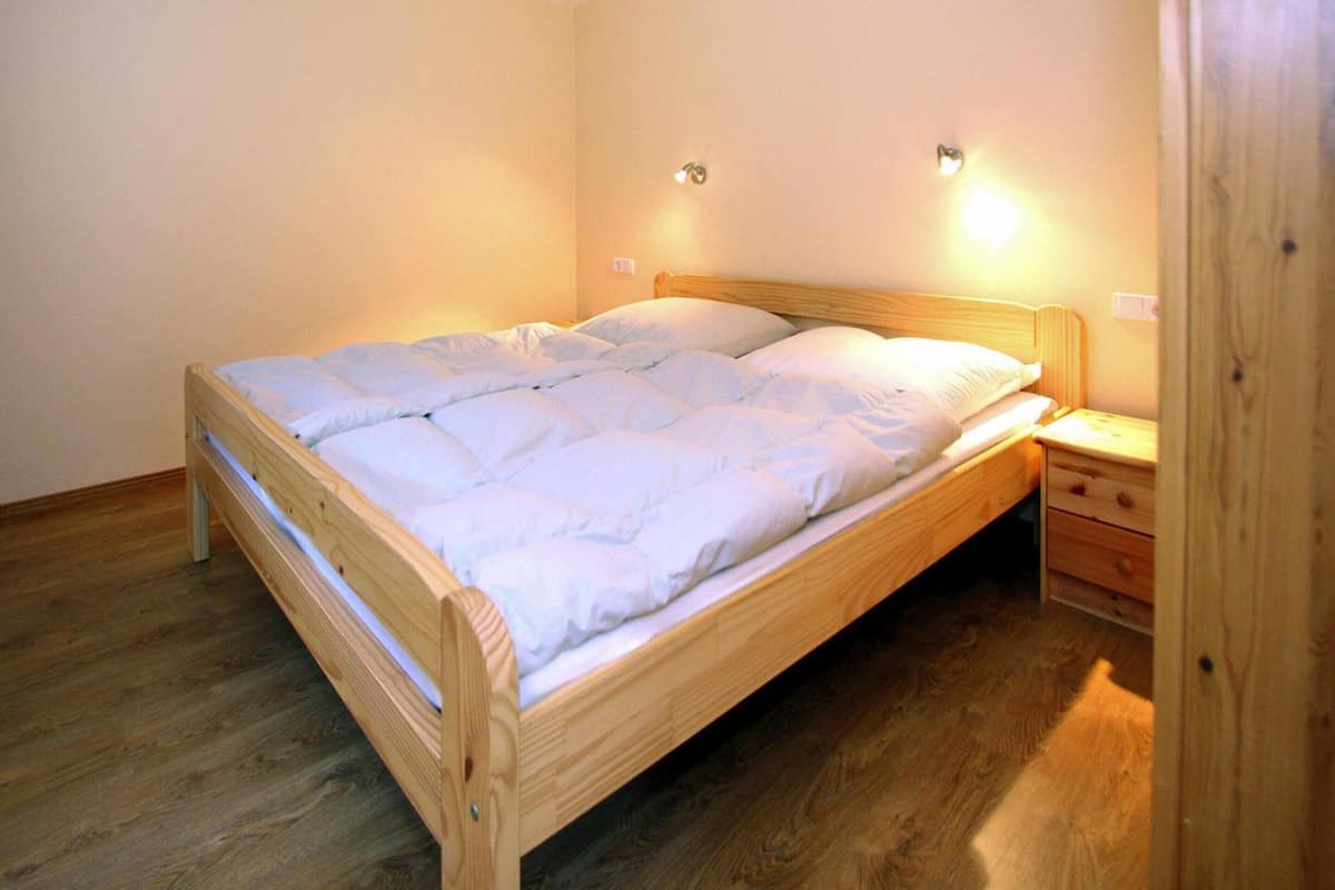 A single bed with a wooden frame, a nightstand, and two wall-mounted lights.