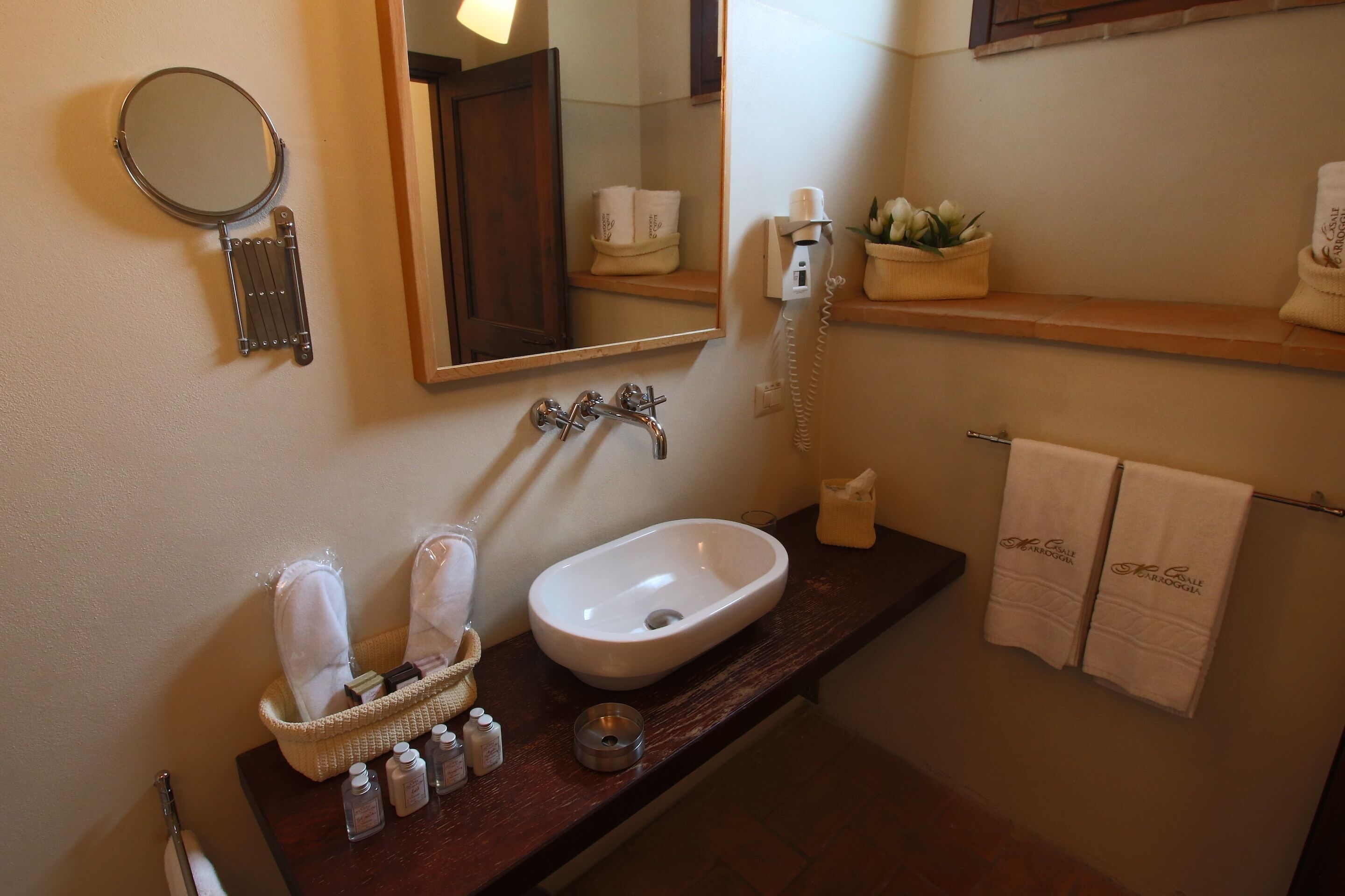 Ein Badezimmer mit einem weißen Waschbecken, einem Spiegel, einem Handtuchhalter und einem Ablagebereich für Toilettenartikel.