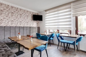 A modern dining area with a wooden table, blue chairs, and a grey sofa. - Classy Apartment in Oberhausen (Oberhausen)