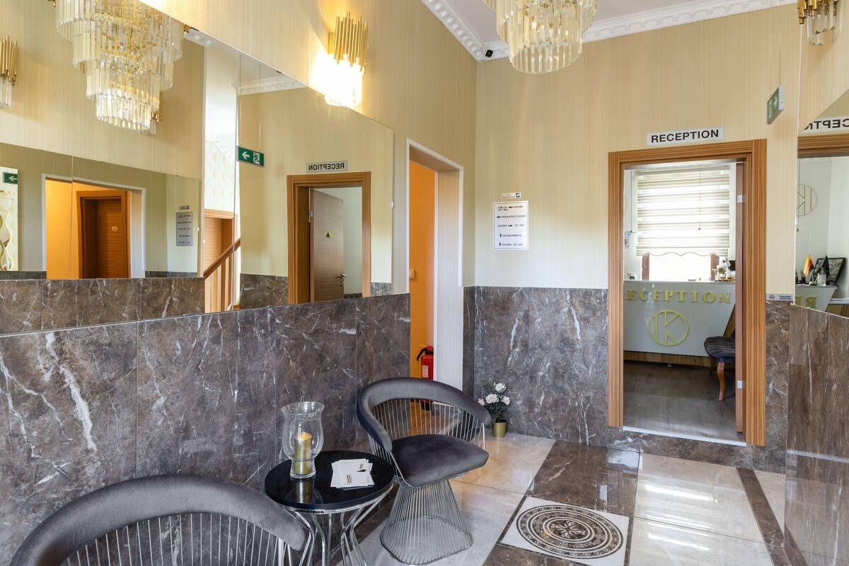 A reception area with marble flooring, a reception desk, and a seating area with chairs and a table.
