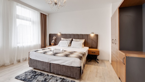 Une chambre à coucher moderne avec un grand lit, une armoire en bois et un lustre.