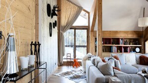 Un accogliente soggiorno con interni in legno, un'ampia finestra e un divano con cuscini decorativi.