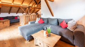 A cozy loft-style living room with a wooden ceiling, a sectional sofa, and a wooden coffee table. - Spacious Holiday Home in Fugenberg With Sauna (Fuegenberg)