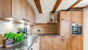 A modern kitchen with wooden cabinets, a built-in oven, and a coffee maker on the counter. - Spacious Holiday Home in Fugenberg With Sauna (Fuegenberg)