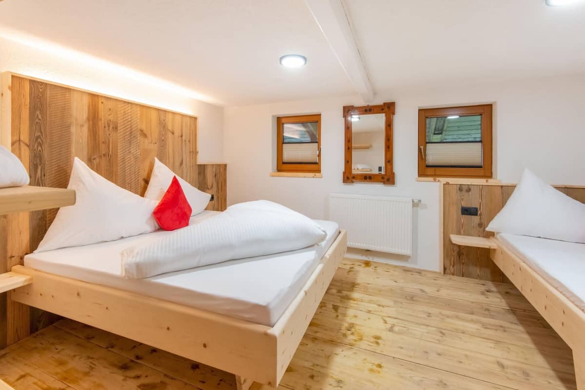 A wooden room with a bed, two bedside tables, a mirror, and a window.