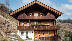 A two-story wooden chalet with balconies, a front door, and a wooden deck leading to the entrance. - Spacious Holiday Home in Fugenberg With Sauna (Fuegenberg)