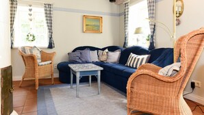 A living room with a sofa, two wicker chairs, a small table, and a painting on the wall. - Semi-detached Houses, Oldsum auf Fohr (Oldsum)