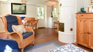 A living room with wicker furniture, a blue sofa, a wooden cabinet, and a painting on the wall. - Semi-detached Houses, Oldsum auf Fohr (Oldsum)