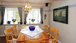 A dining room with a wooden table, six chairs, a chandelier, and a window with curtains. - Semi-detached Houses, Oldsum auf Fohr (Oldsum)
