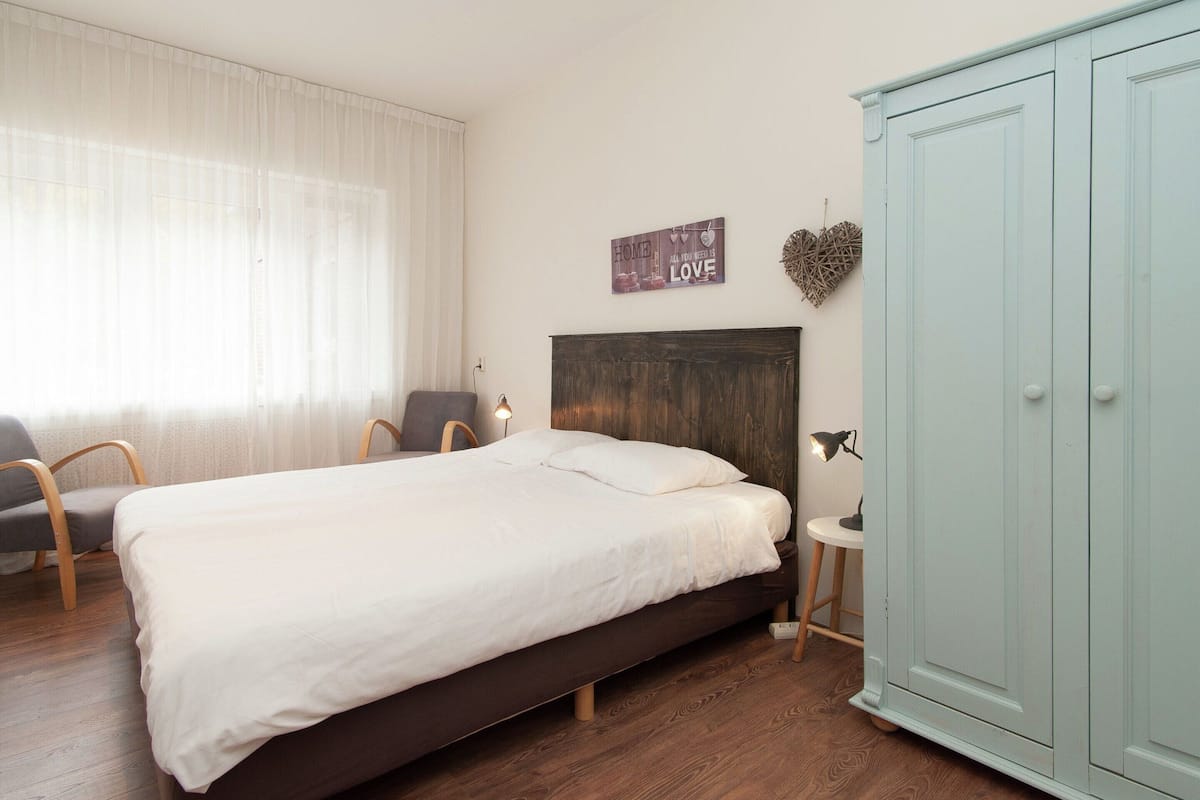 Un dormitorio con cama, una silla, un armario y un adorno en la pared.