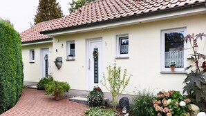 Une maison de plain-pied avec un toit en tuiles, une porte d’entrée et un petit porche.