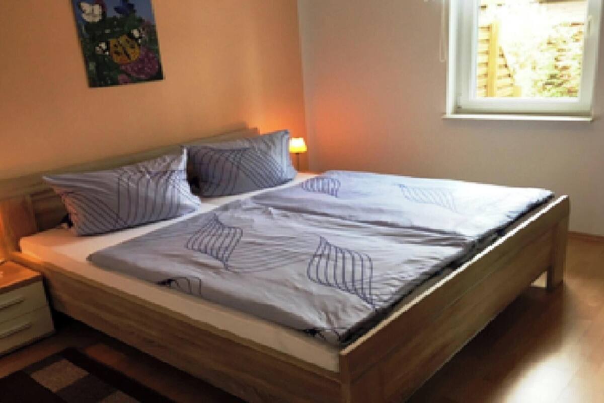 A bed with a wooden frame, two bedside tables, and a window with a view.