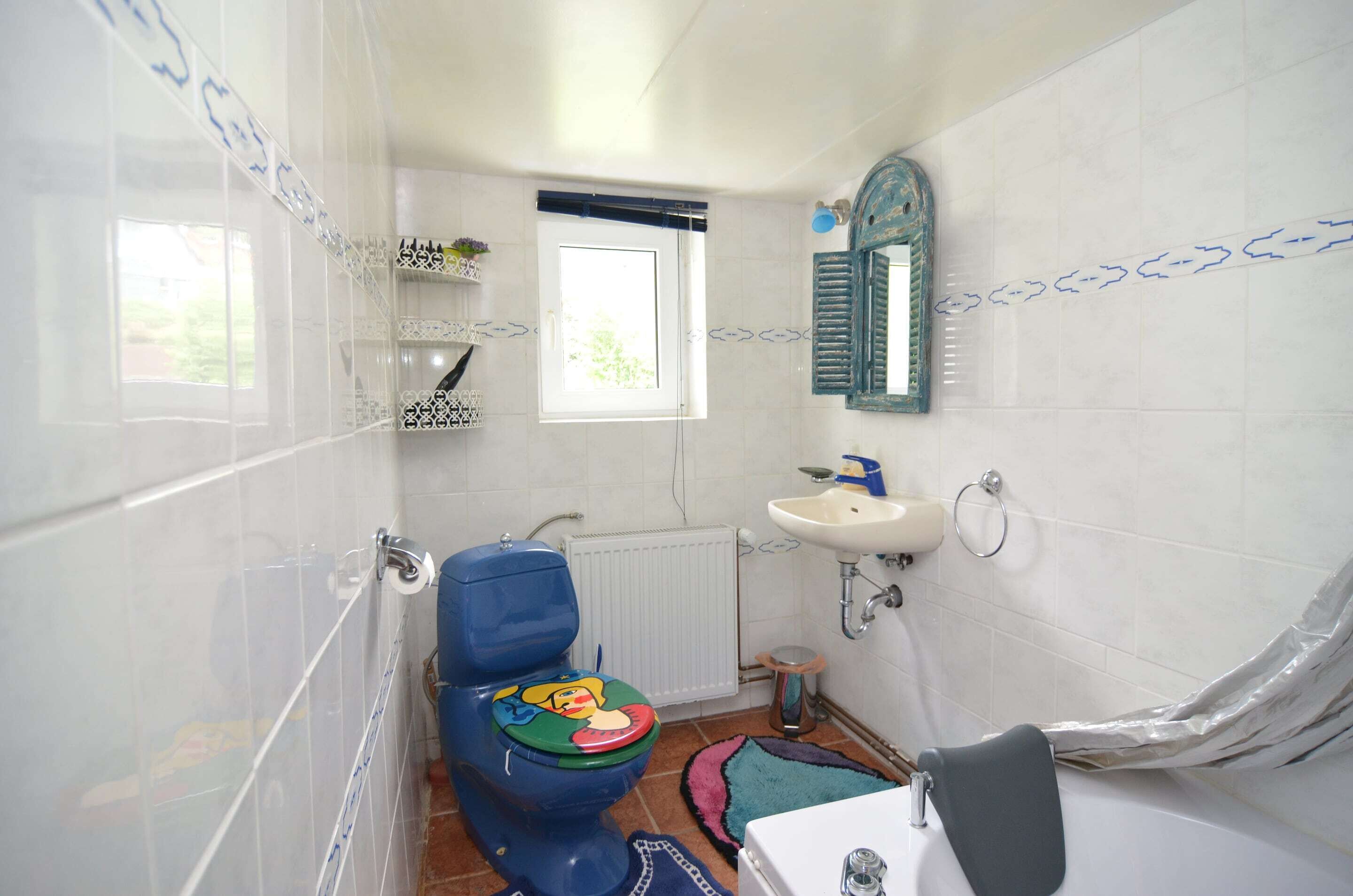 A bathroom with a toilet, sink, and window.
