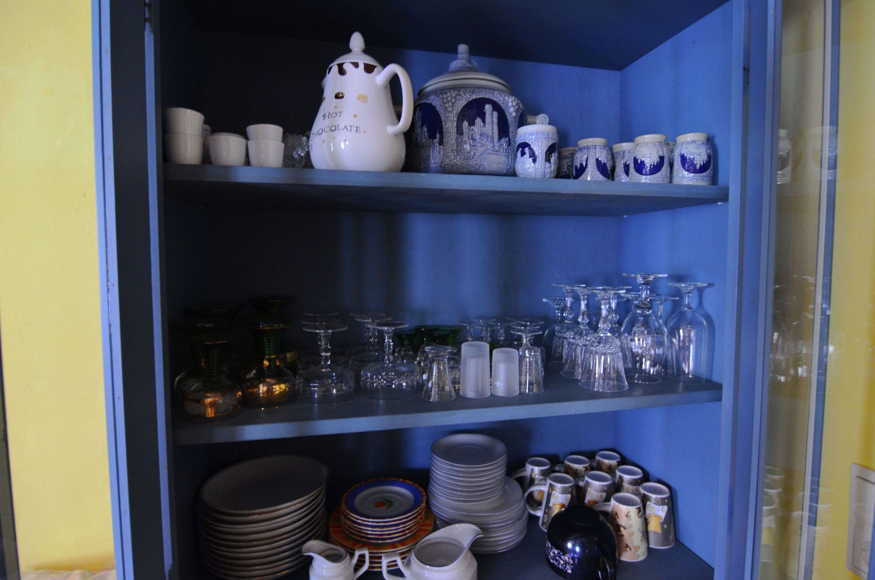 A kitchen with shelves holding various kitchenware, including plates, cups, and glassware.