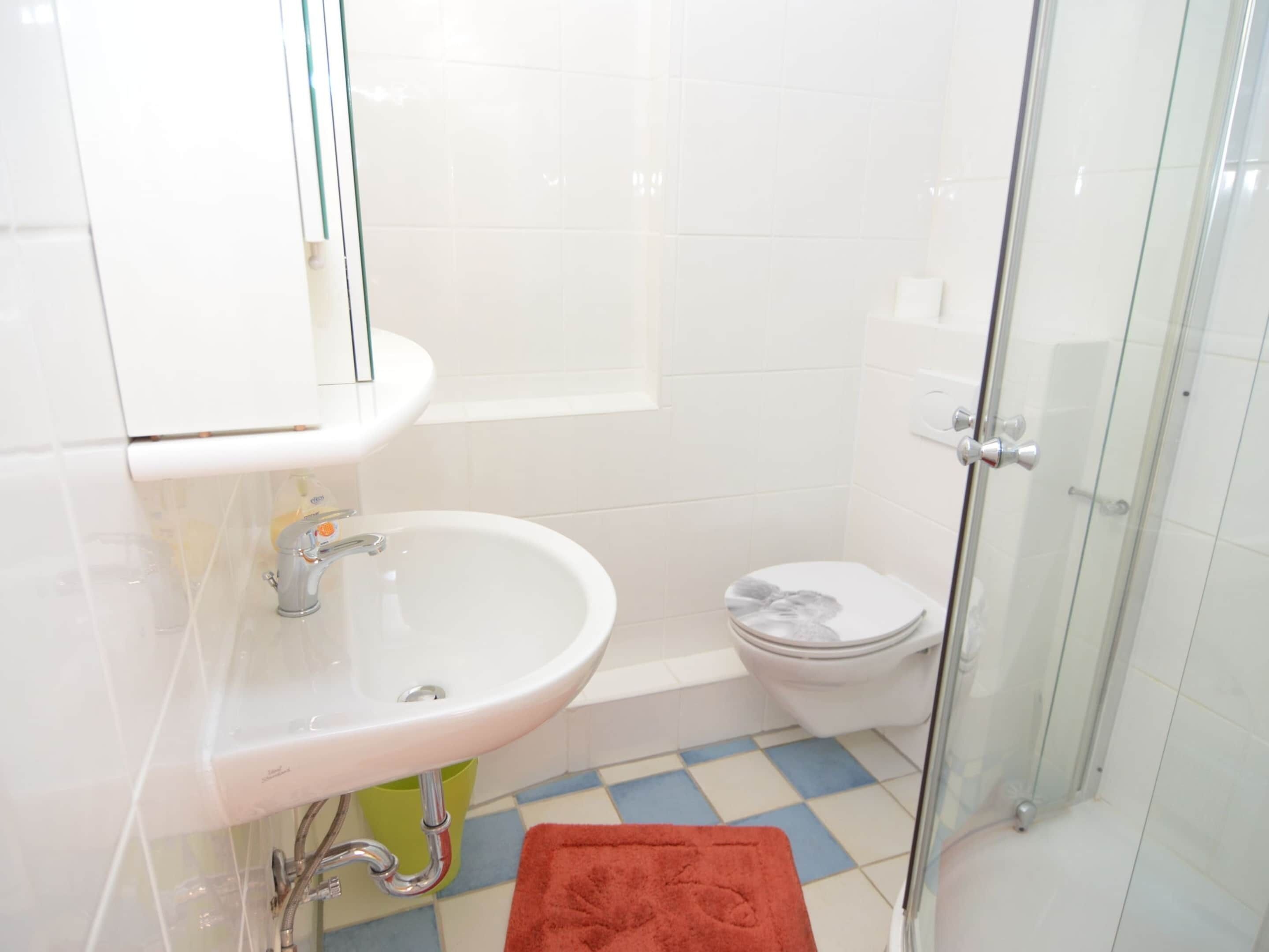 Une salle de bain avec un lavabo blanc, des toilettes et un espace douche.