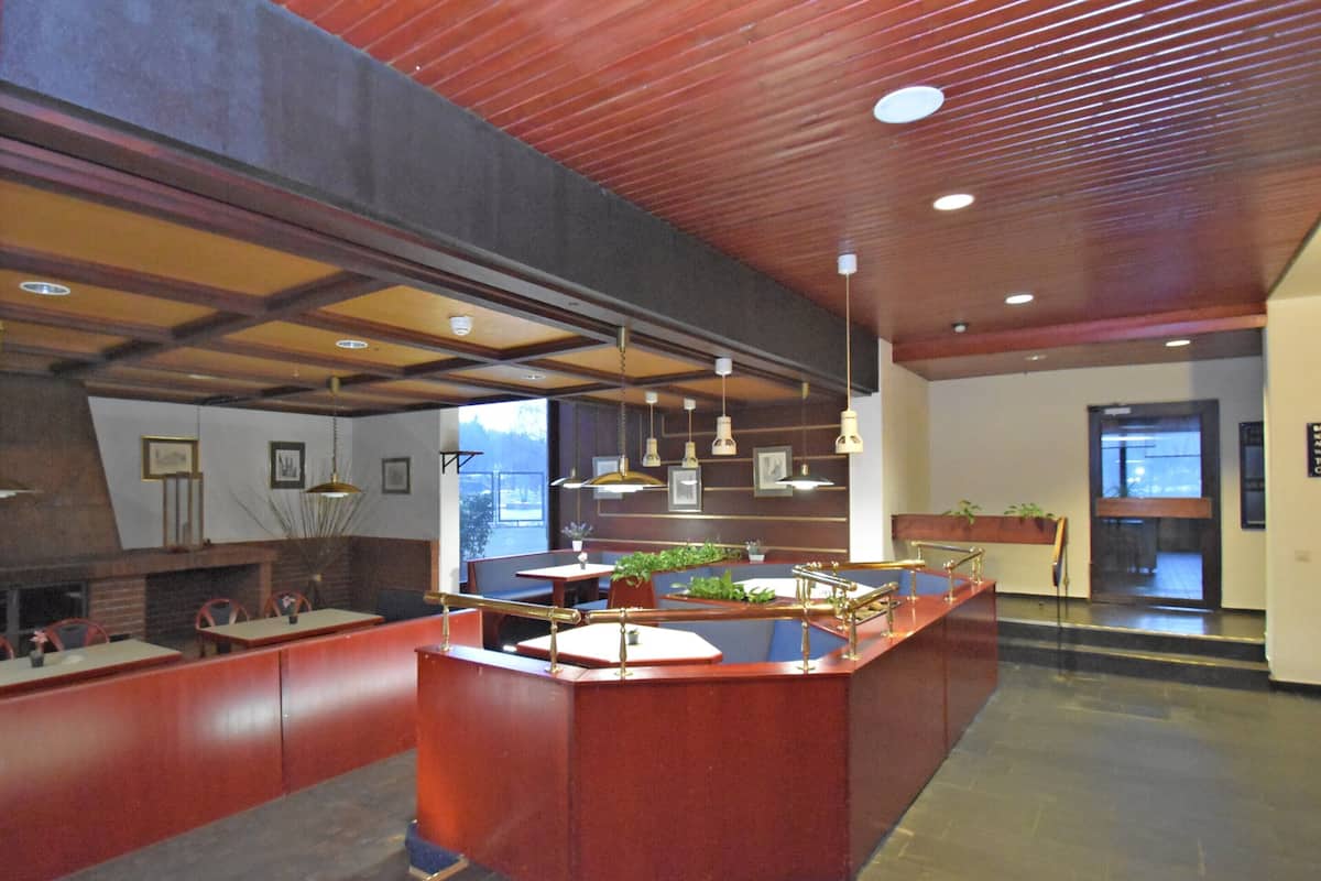 A modern restaurant with a central island, wooden ceiling, and pendant lighting.