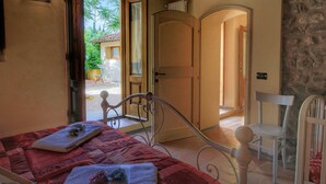 A bedroom with a bed, a chair, a wardrobe, and a view of the outside. - Modern Holiday Home in Castelfranco di Sopra With Swimming Pool (Castelfranco Piandisco)