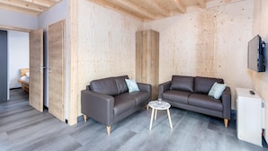 Una habitación moderna con dos sofás, una mesita y un televisor.
