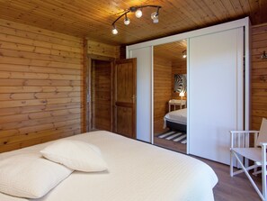 Una habitación con paneles de madera, una cama, una silla y un armario.