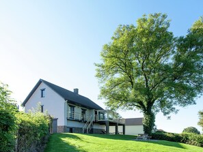 Una casa moderna de dos pisos con un árbol grande en el jardín delantero.
