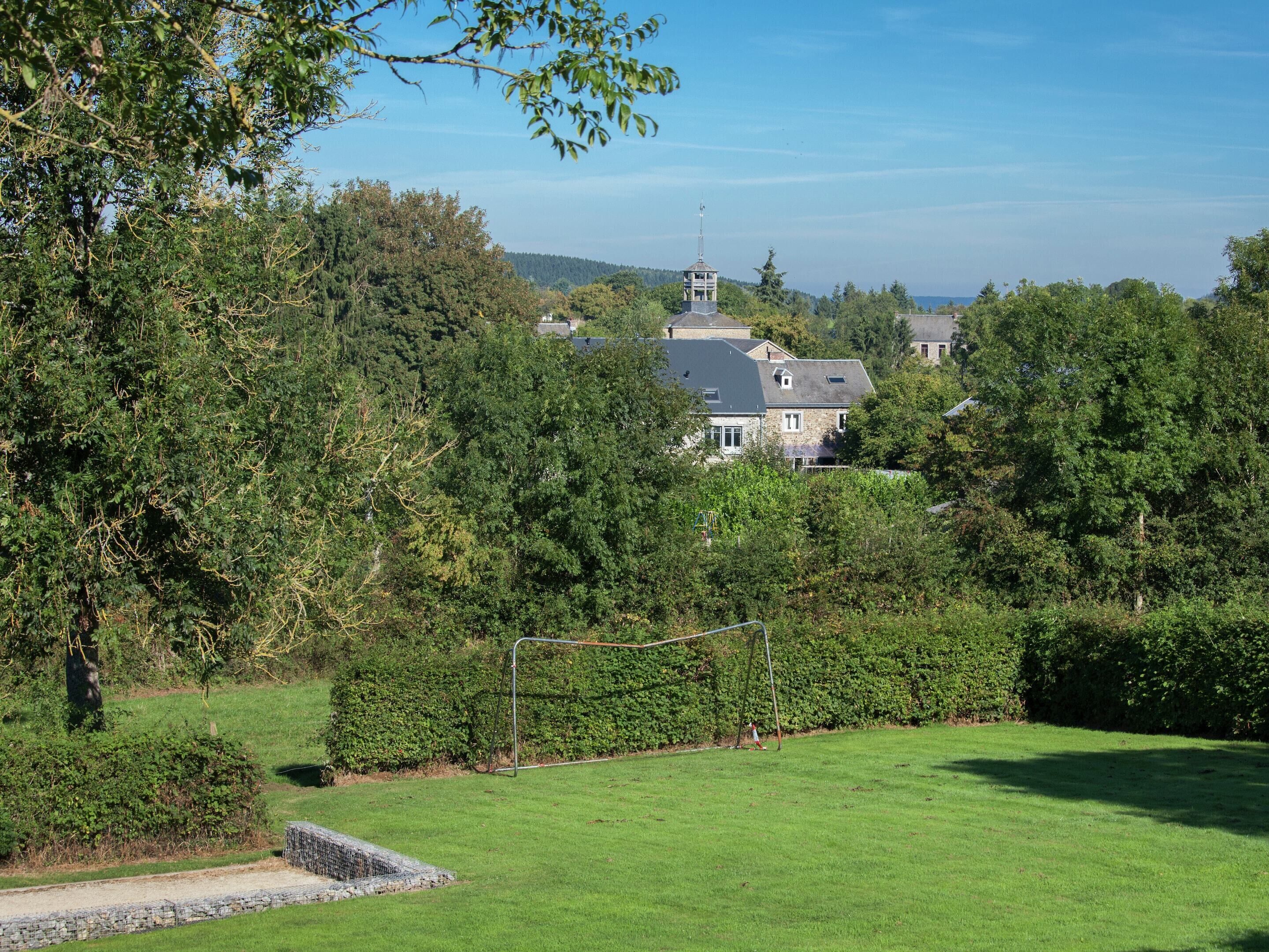 Une grande maison entourée d’arbres denses et d’une pelouse bien entretenue.