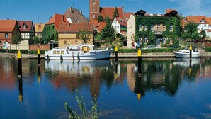A riverside town with historic buildings, a prominent tower, and boats docked along the water. - Ferienwohnung in Plau am See (Plau am See)