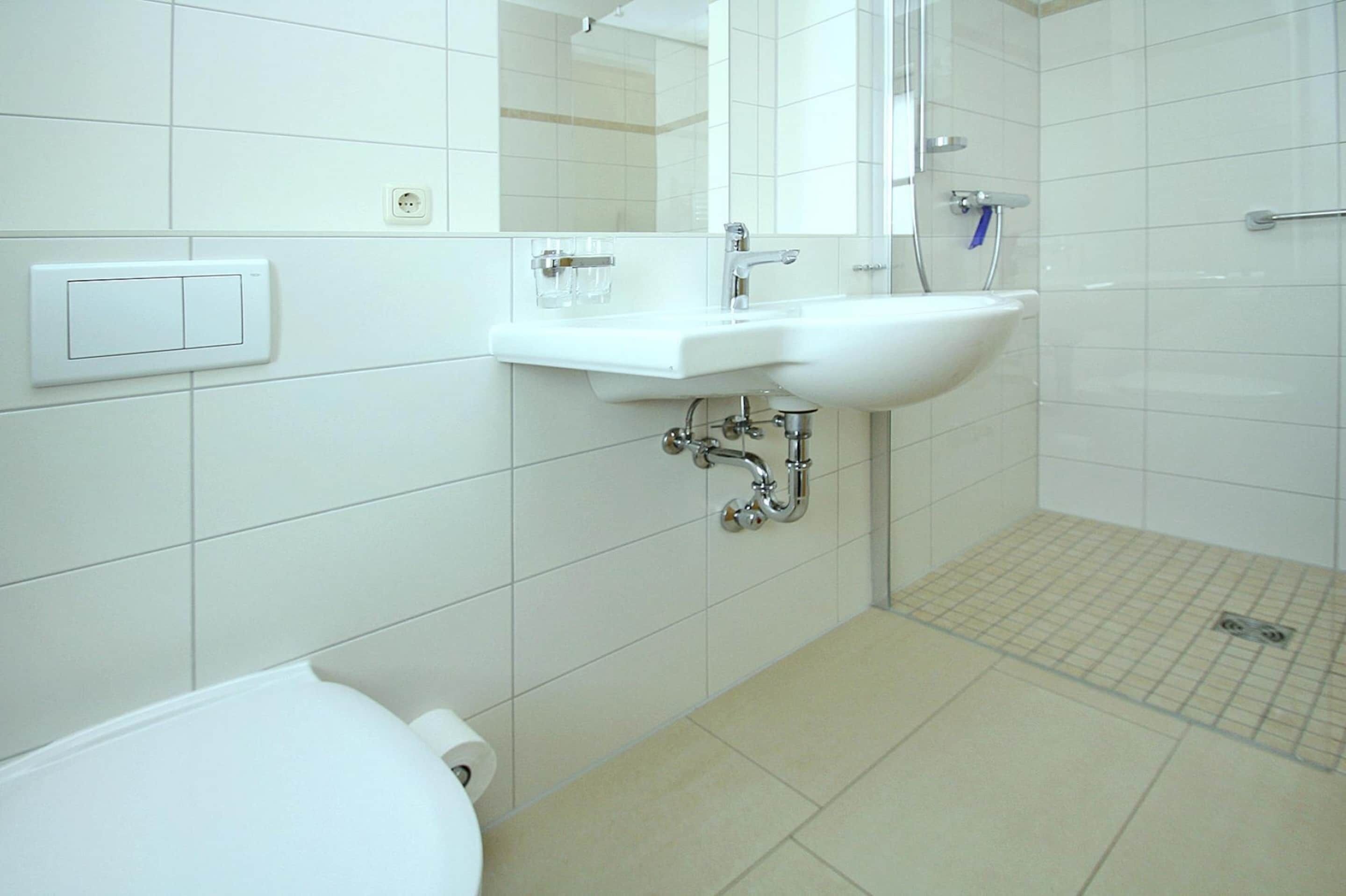 Un bagno con lavandino, specchio e WC bianchi.