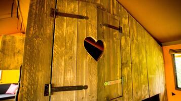 A wooden door with a heart-shaped cutout, metal hinges, and a small window.