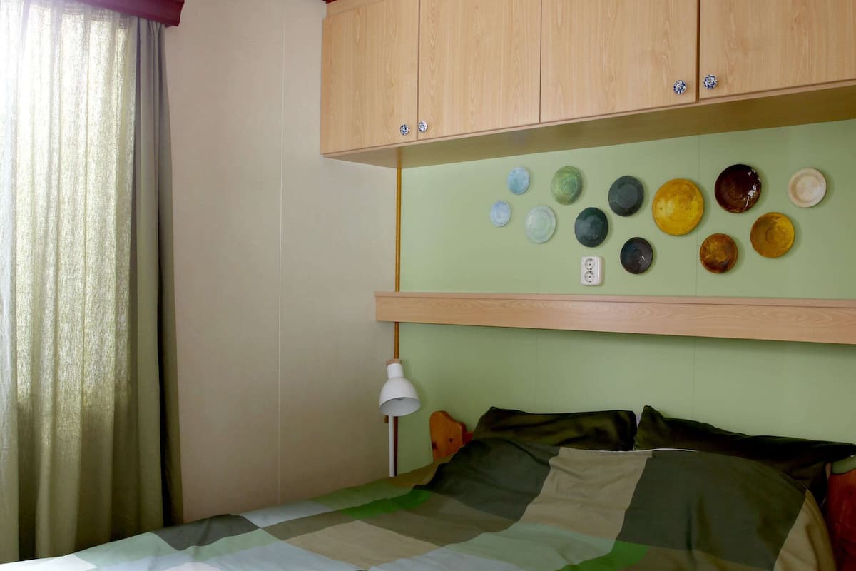 Una habitación con una cama, una lámpara y una pared decorada con varios platos.