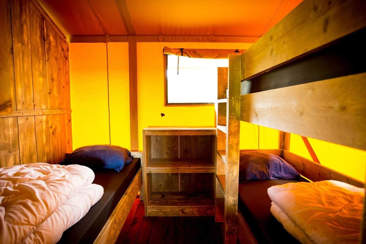 Una cabaña con literas de madera, un pequeño escritorio de madera y una ventana que proporciona luz natural.