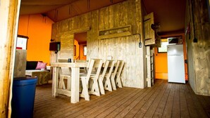 A rustic wooden interior with a dining area, a refrigerator, and a trash bin.
