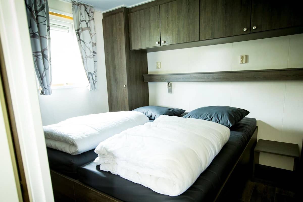 Un dormitorio con dos camas, armarios de madera y una ventana con cortinas.