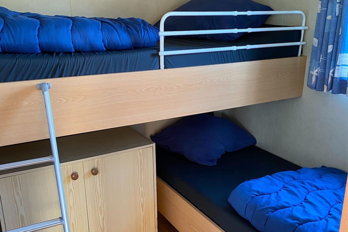 Una cama litera con una cama inferior y un pequeño armario de madera debajo.