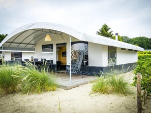 Une maison de plage moderne dotée d’un patio couvert, d’un espace salon extérieur et d’une terrasse en bois.