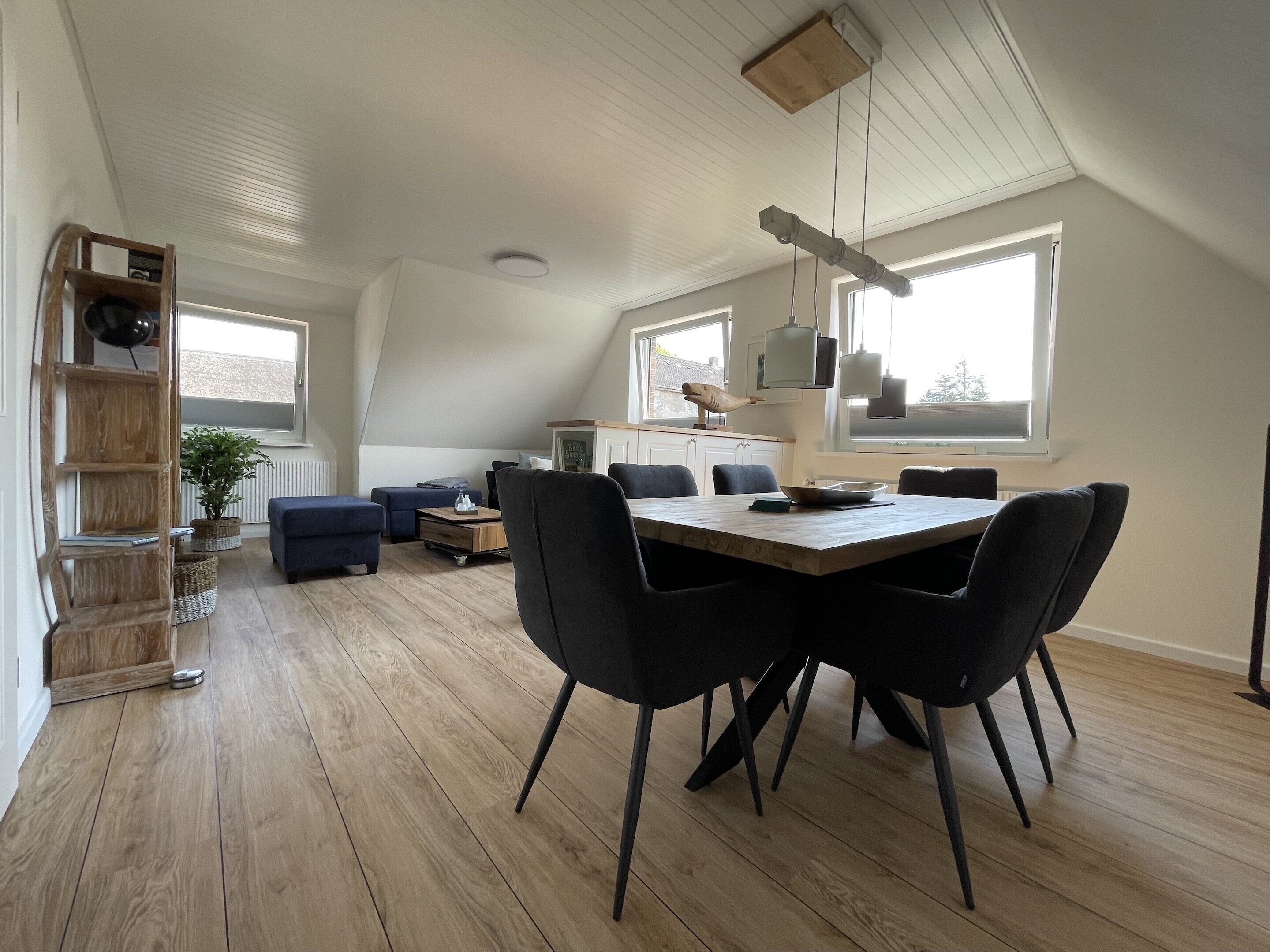 A modern loft apartment with a dining area, a loft bed, and a kitchen.