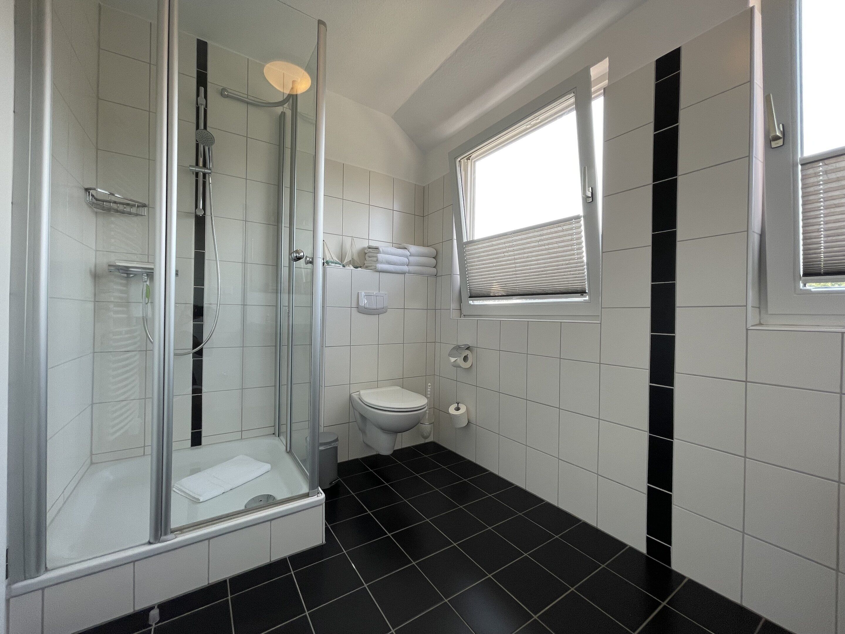 A bathroom with a glass-enclosed shower, a toilet, and a window.