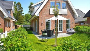 A two-story house with a brick facade, a sloped roof, and a small patio with outdoor furniture. - Apartments, Wyk auf Foehr (Wyk auf Foehr)
